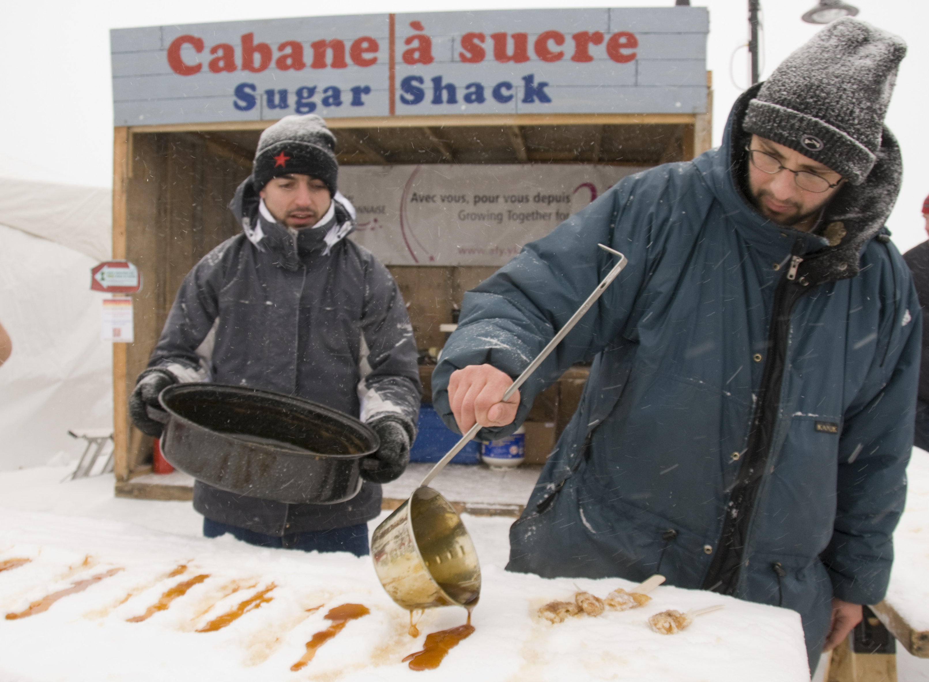 Two people make maple syrup toffee on ice at Yukon Rendezvous Festival in Whitehorse