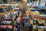 People walking past food vendors at an indoor market