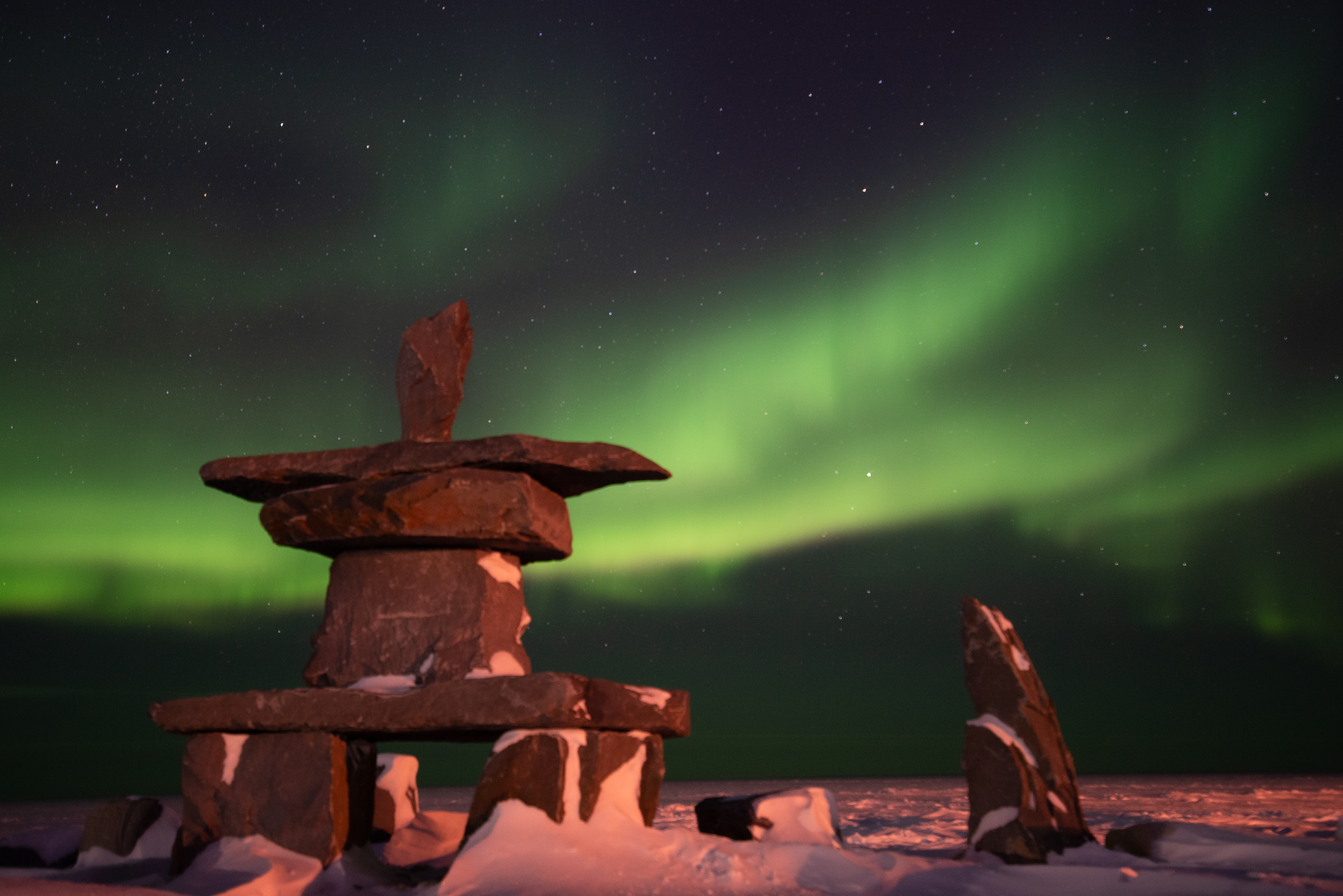 The northern lights shining above the Churchill inukshuk.