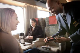 VIA Rail attendant converses with woman seated in train car