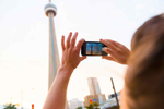 A person looking up at the CN Tower and taking a photo on their phone