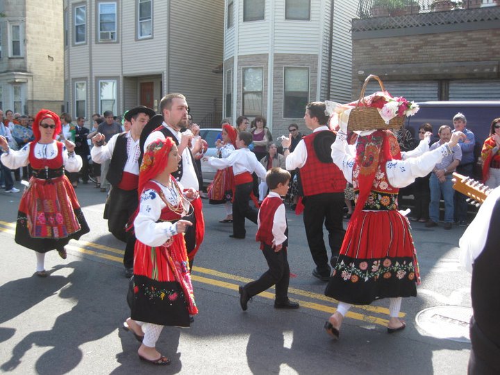 A group dressed in traditional Portuguese outfits dance in the street