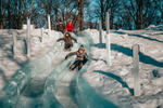 Children enjoying sliding down an ice slide in the snow
