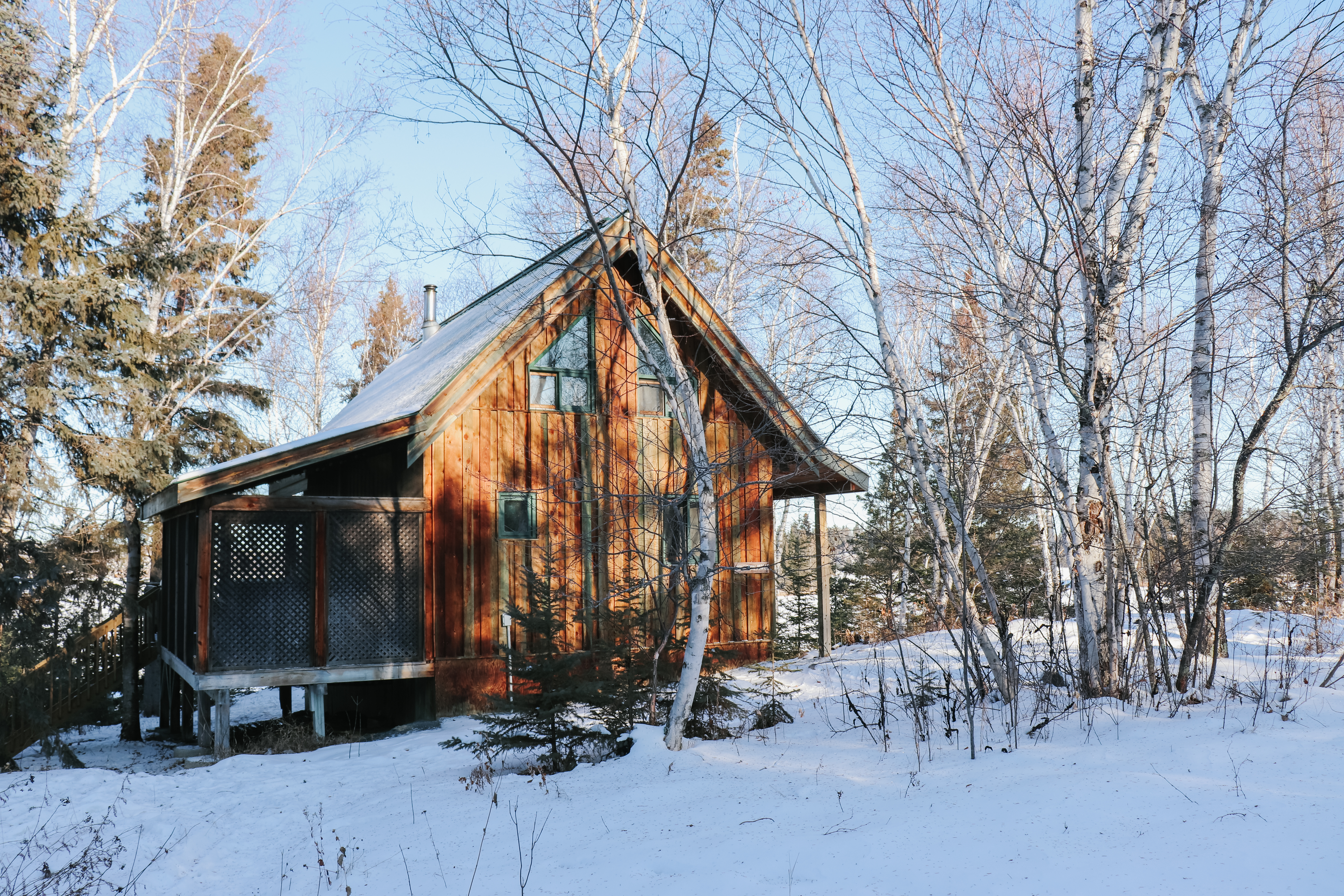 A wooden cabin in a snowy forest on a sunny day
