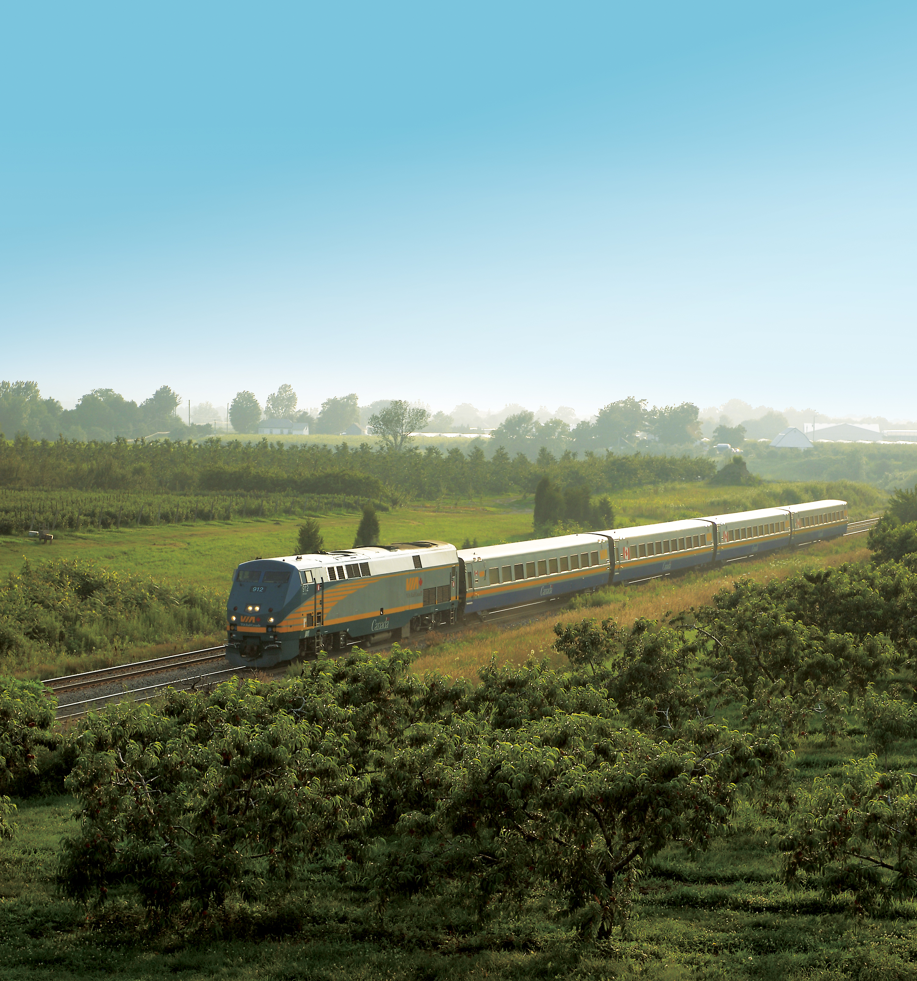 A train rolls through a green field to Niagara Falls on a clear day