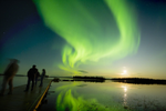 People standing on a dock and watching the Northern Lights in Northern Manitoba