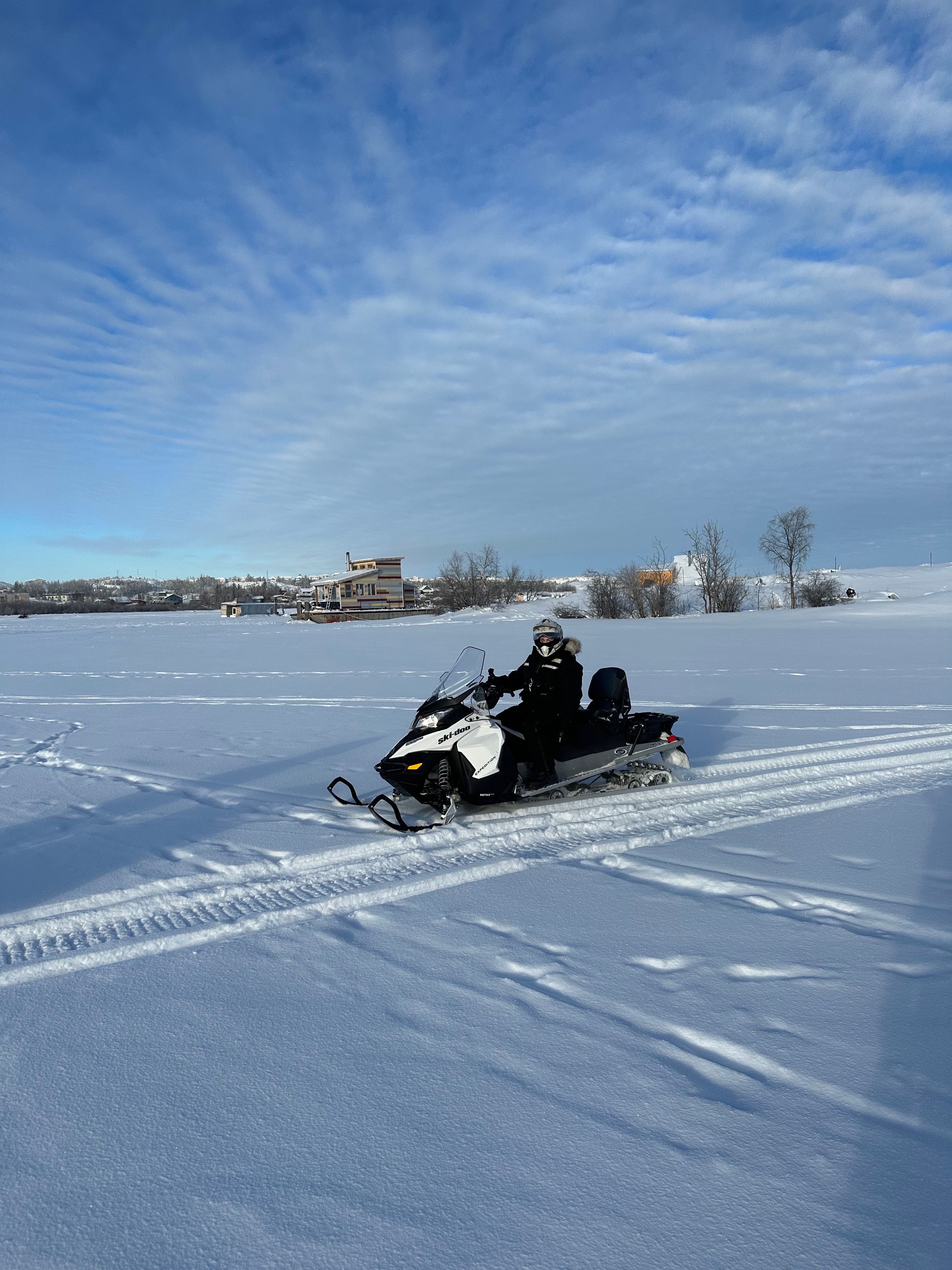 A person is riding a snowmobile through a snowy field