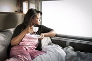 Woman enjoys hot drink in bed and looks out VIA train window