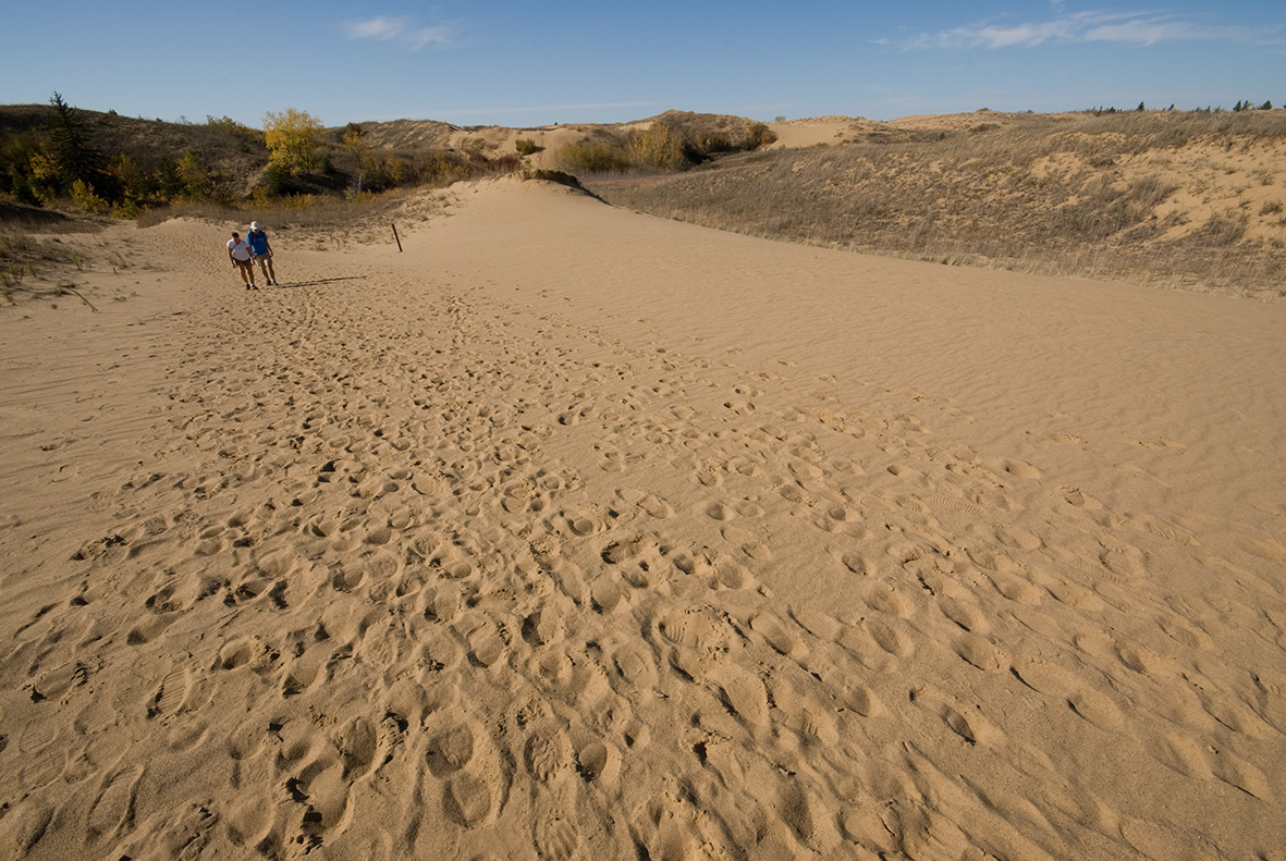 A couple walk along sand dunes on a summer day in Spruce Woods Provincial Park