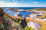 Woman standing on a hill and looking at the ocean and rugged coastline