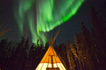 Green Northern Lights in the sky above a teepee at Aurora Village