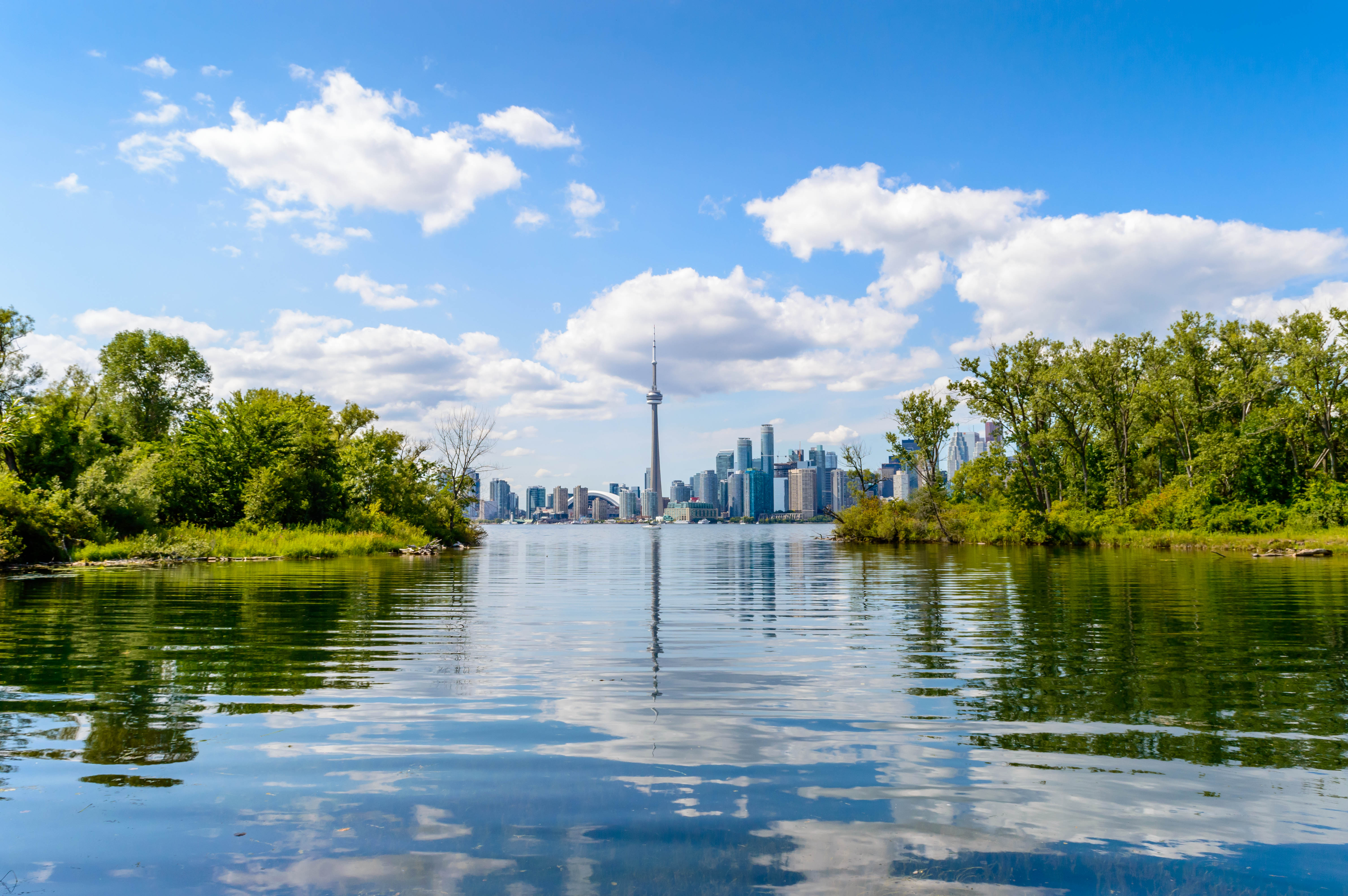 View of modern cityscape from across water and framed by lush islands