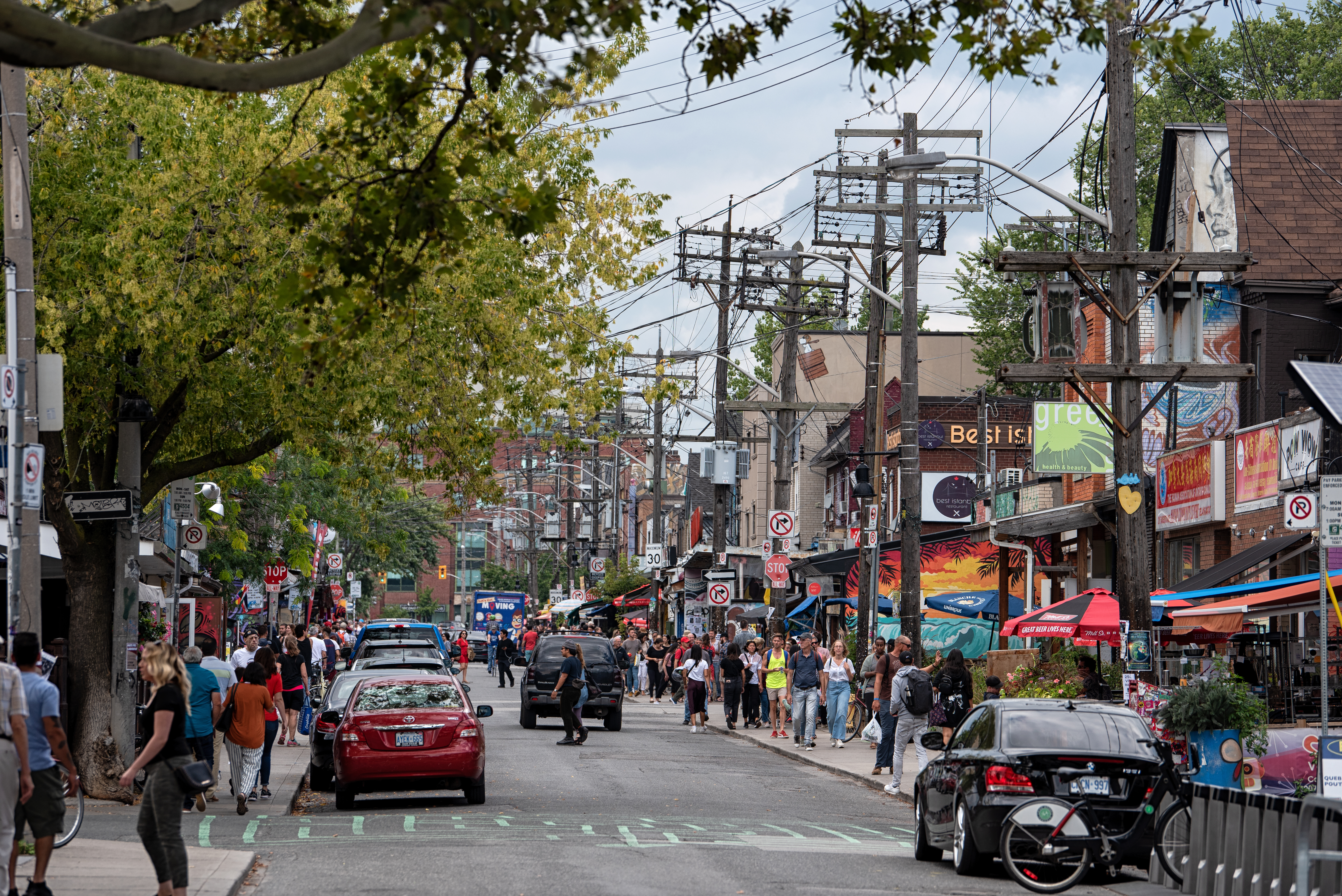View of people walking and cars parked along a busy street 
