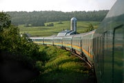 The Via Rail Ocean Train rounds a bend in the track, in a rural area.