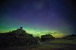 Green Northern Lights in a starry sky above a historical site in Newfoundland