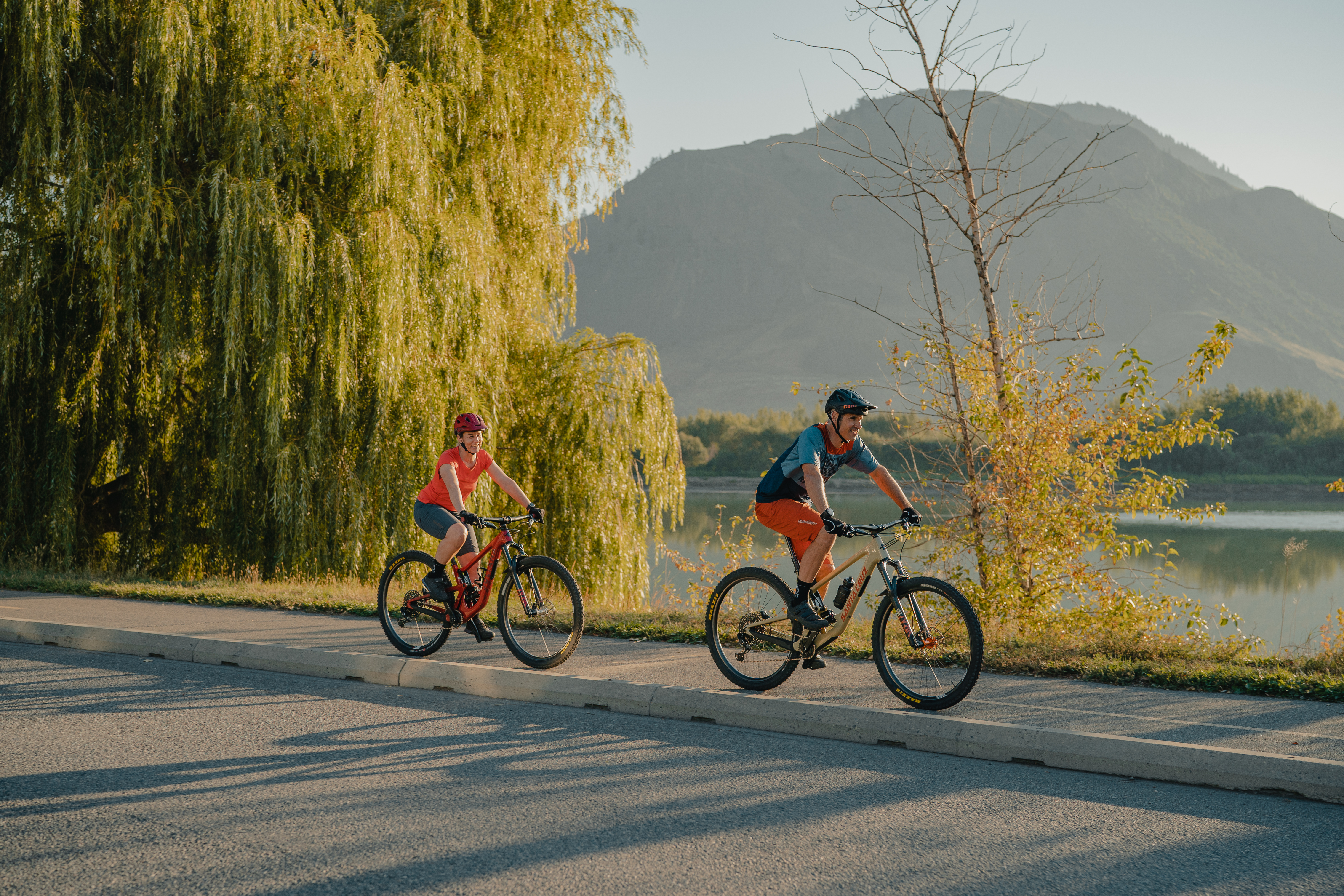 Two people cycle down the Kamloops Rivers trail next to the water