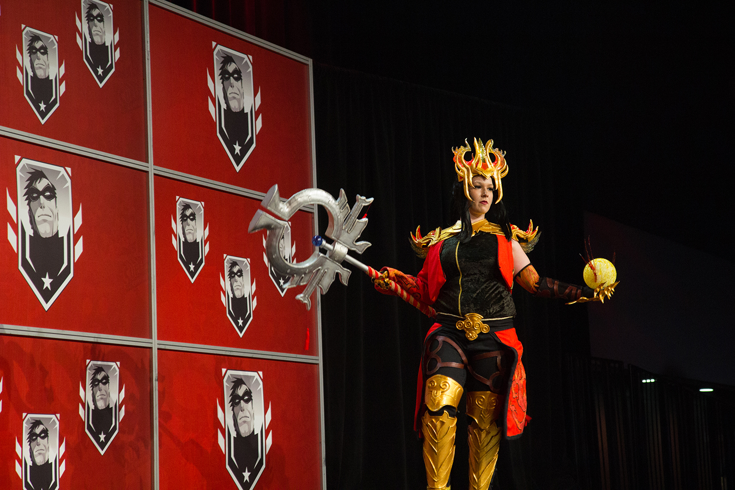 A person dressed in a fantasy superhero costume stands on a stage at Montreal Comiccon