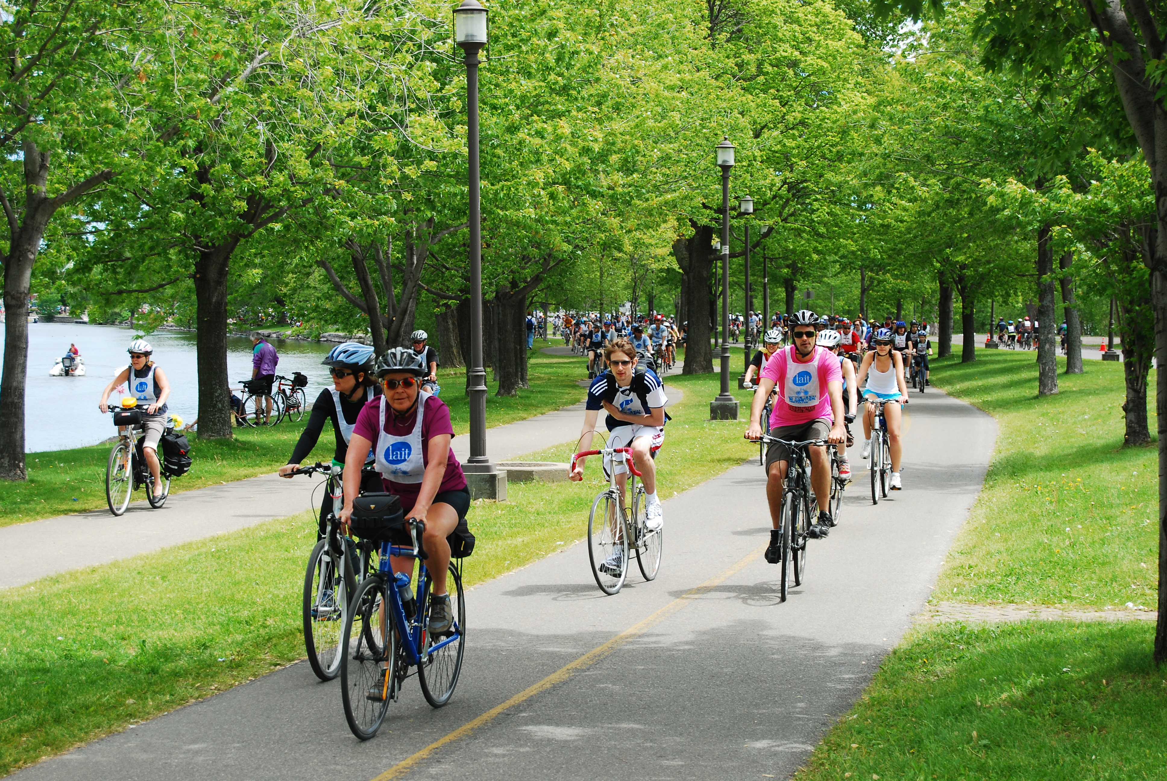 Cyclists competing in a race on a pathway through a park by the water in Montreal