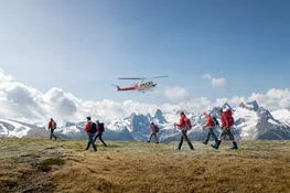 Group of hikers atop mountain with helicopter in background