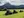 Small group on an ATV tour, going through green grassy field with mountains in the distance