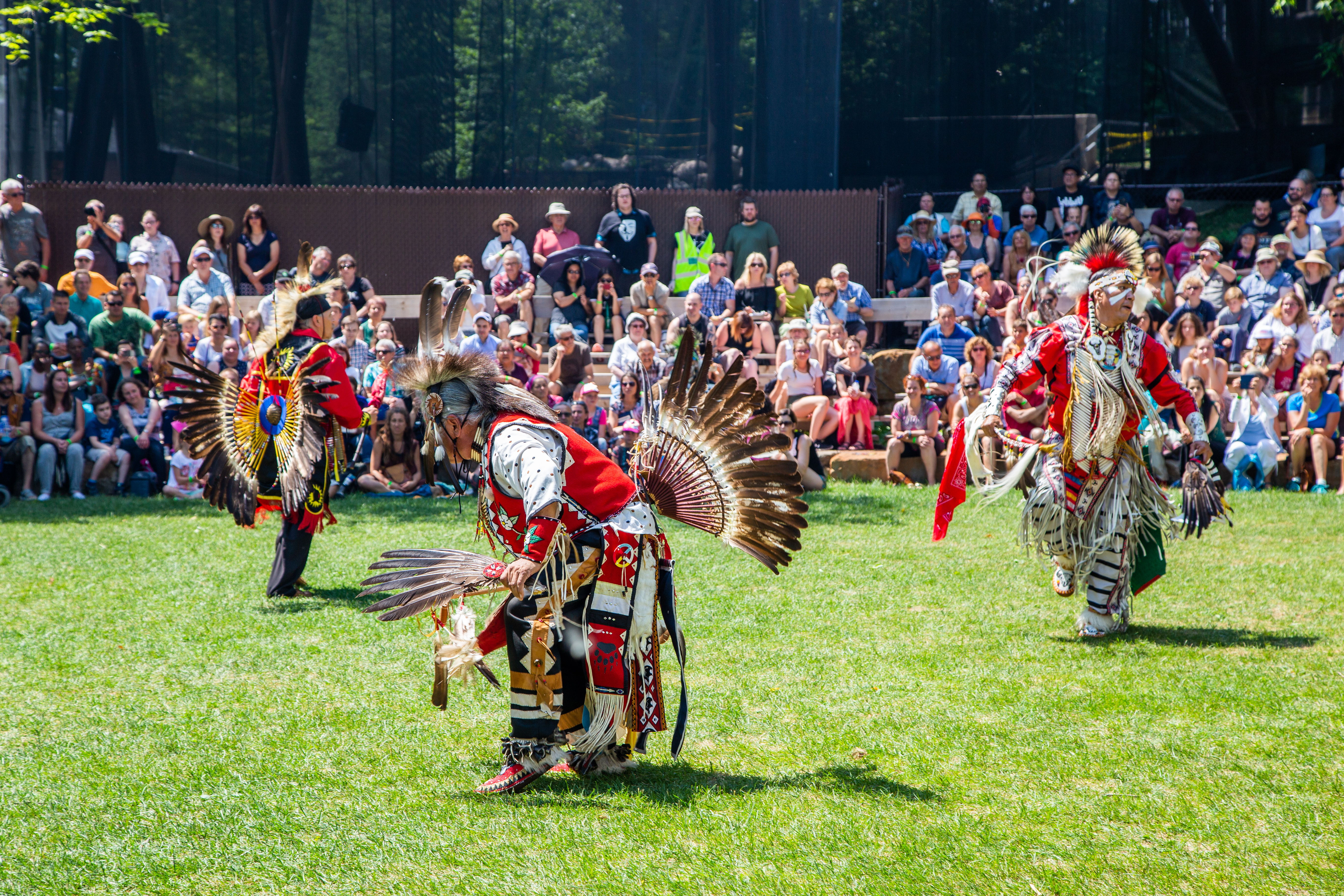 Audience watches as First Nations, wearing traditional garb, group perform at Quebec's annual Wendake International Pow Wow gathering