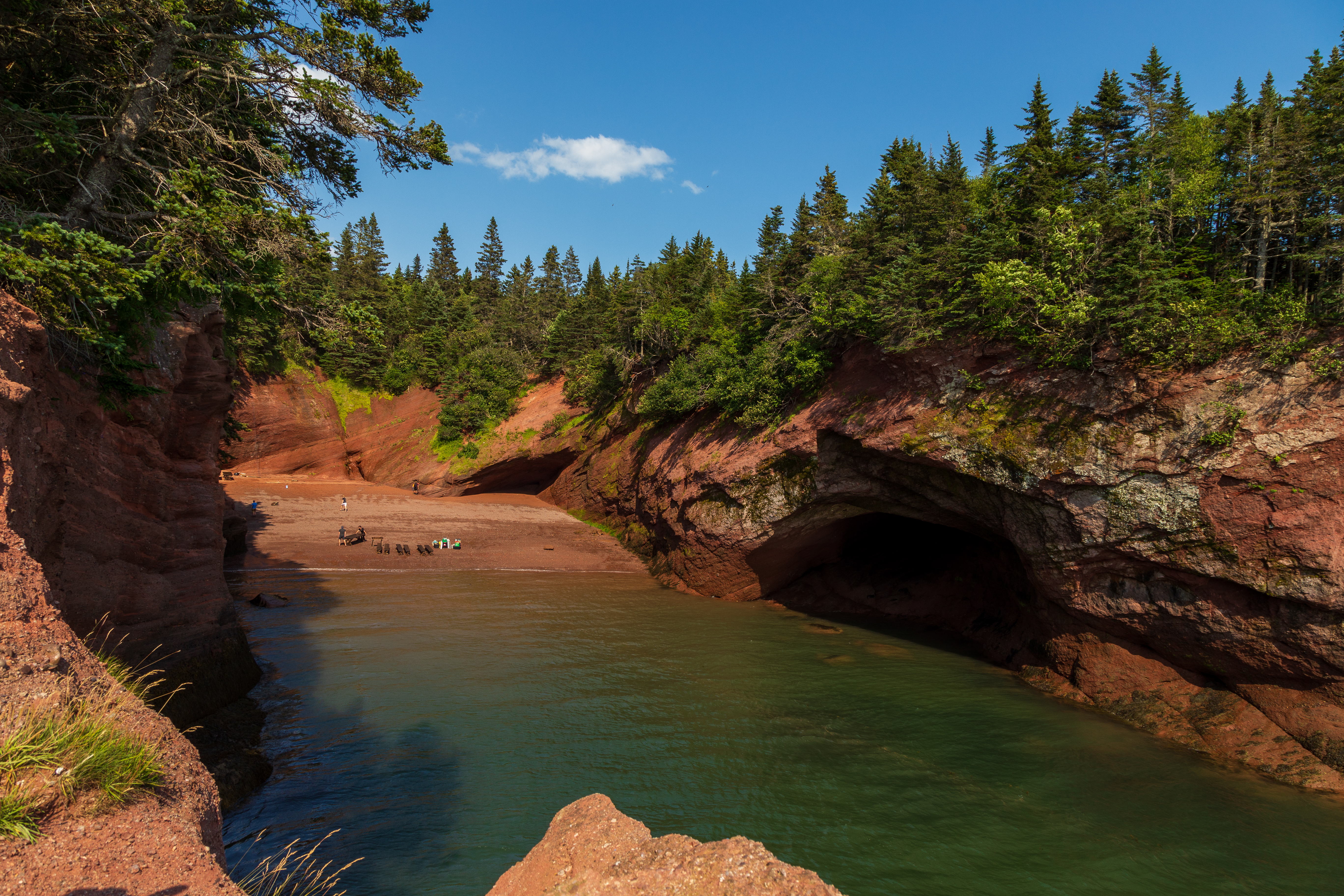 Tides from Bay of Fundy reach eroded red Sandstone Cave opening at St. Martins sea caves in Bay View, New Brunswick