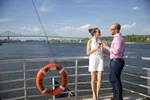 A couple stand on the outside deck of a boat cruising the St. Lawrence River