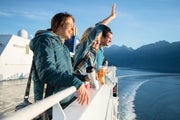 Three friends wave from deck of ferry boat
