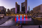 Water feature in front of a Toronto light sign and modern city buildings