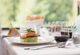 A plate of grilled salmon served with red wine in the GoldLeaf dining car onboard the Rocky Mountaineer.