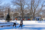 Two people ice skating on a frozen lake in Mount Royal Park during winter