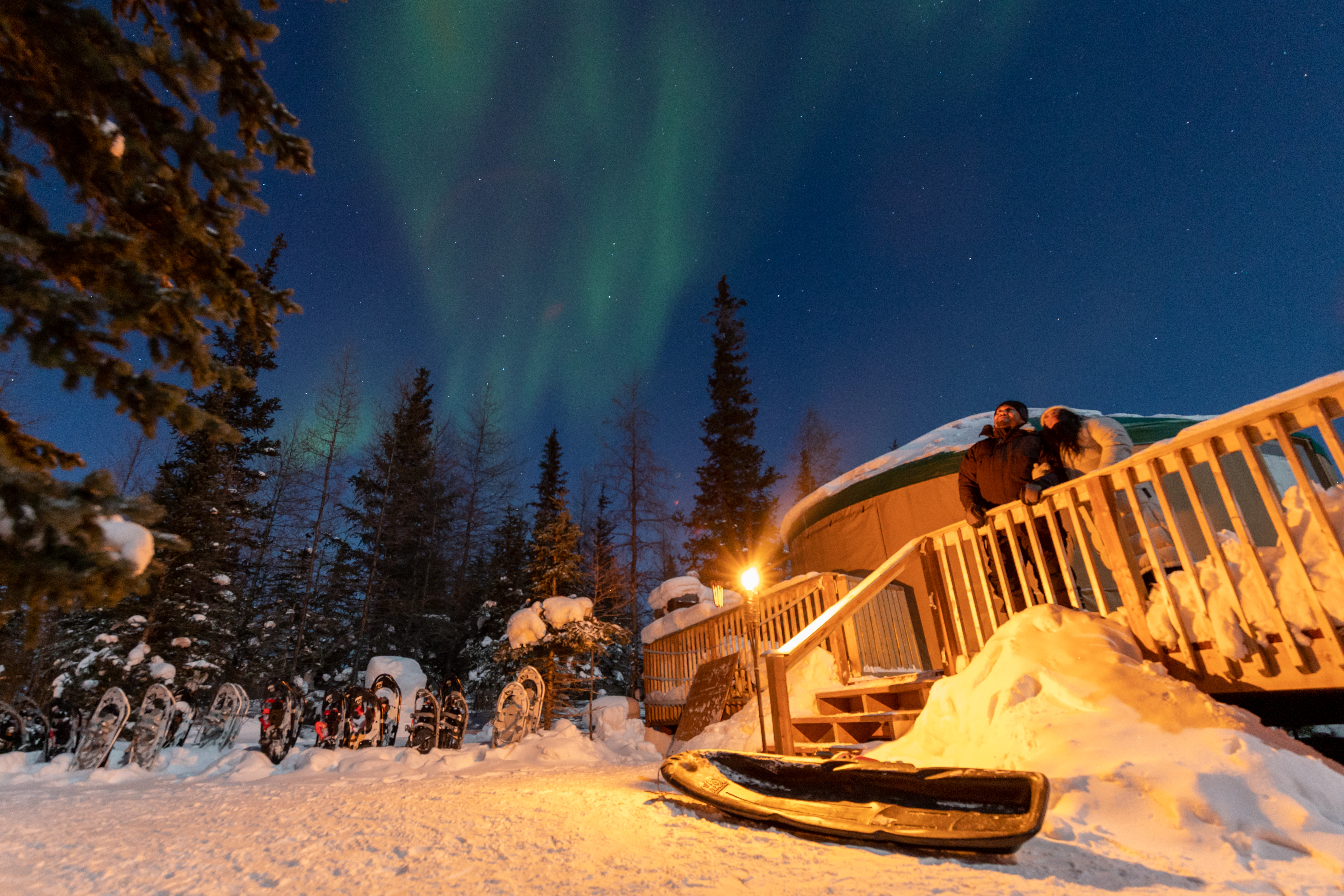 Couple stand near yurt where Northern Lights are visible in Churchill, Manitoba