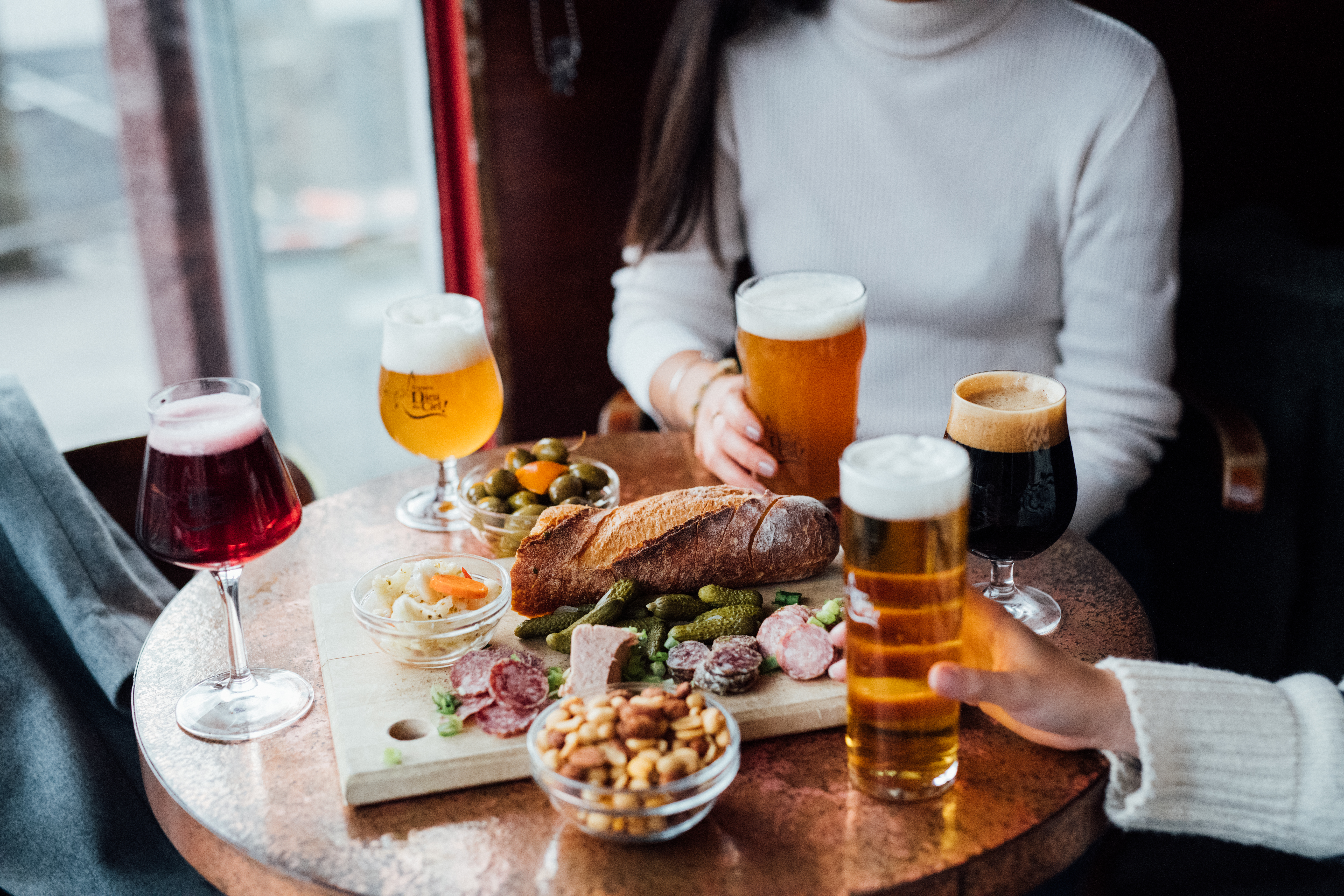 People sit around a table with glasses of beer and a charcuterie board at Dieu du Ciel 