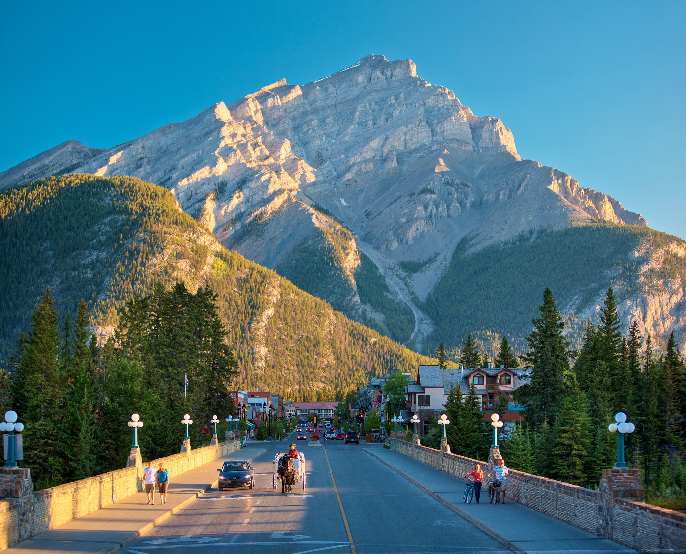 Banff Avenue, a busy street in Banff, is in front of towering mountains 