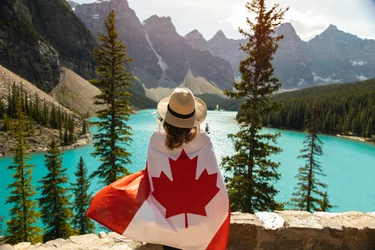 Woman with Canada flag wrapped around her overlooking Moraine Lake