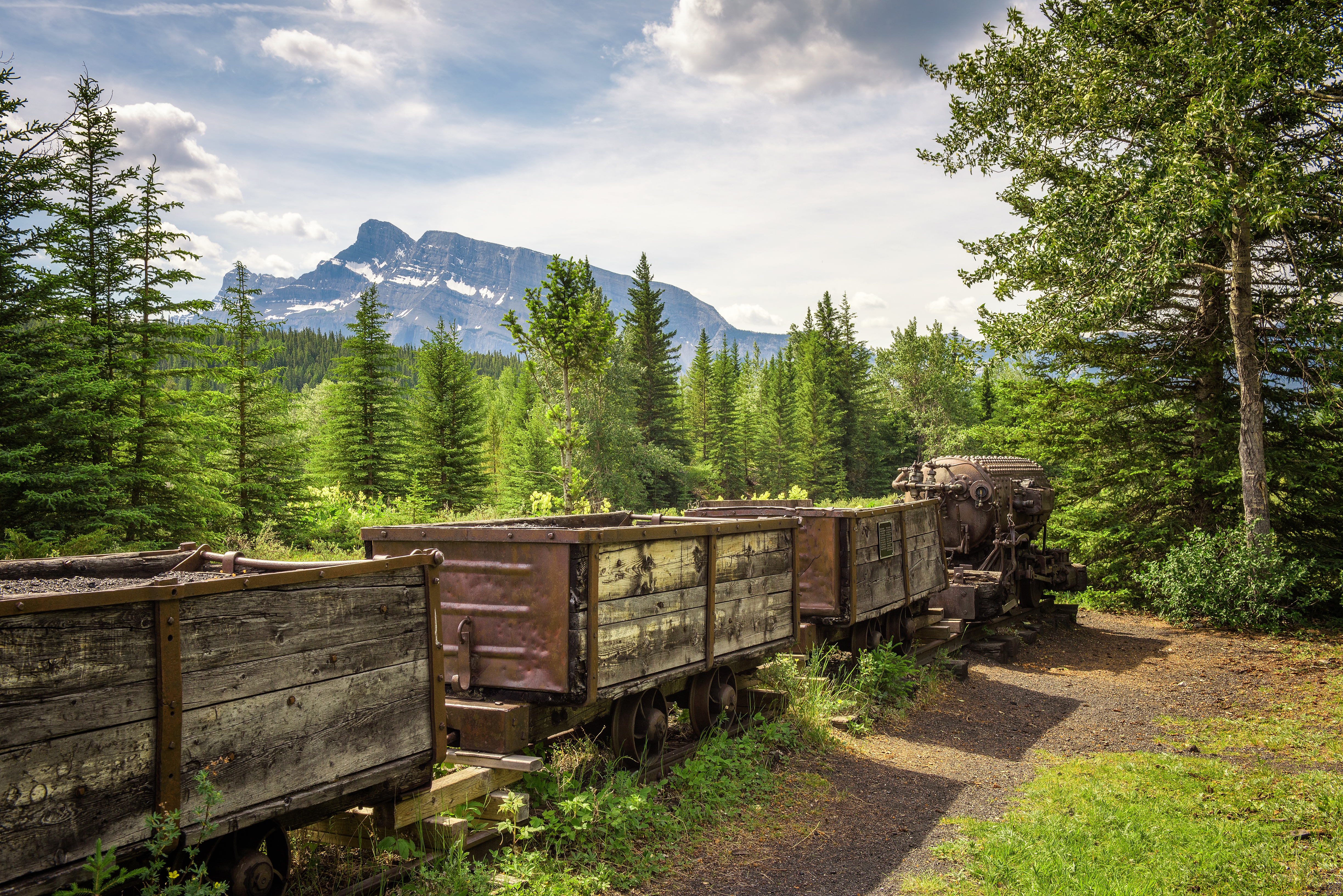 Abandoned old train on display for exhibit on ruins of mining operation near Banff with Mount Rundle in view