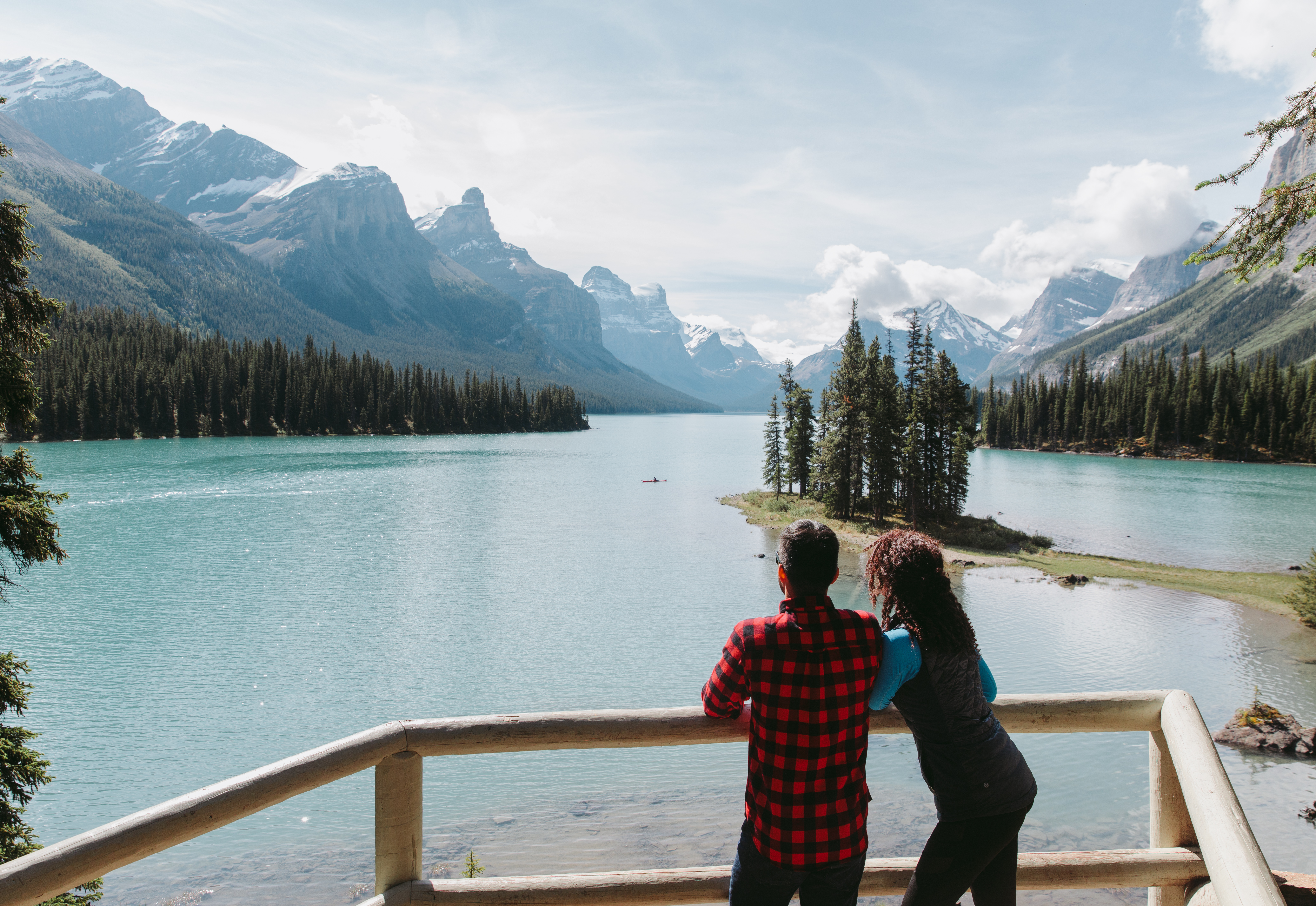 A couple stands on a dock overlooking Maligne Lake.