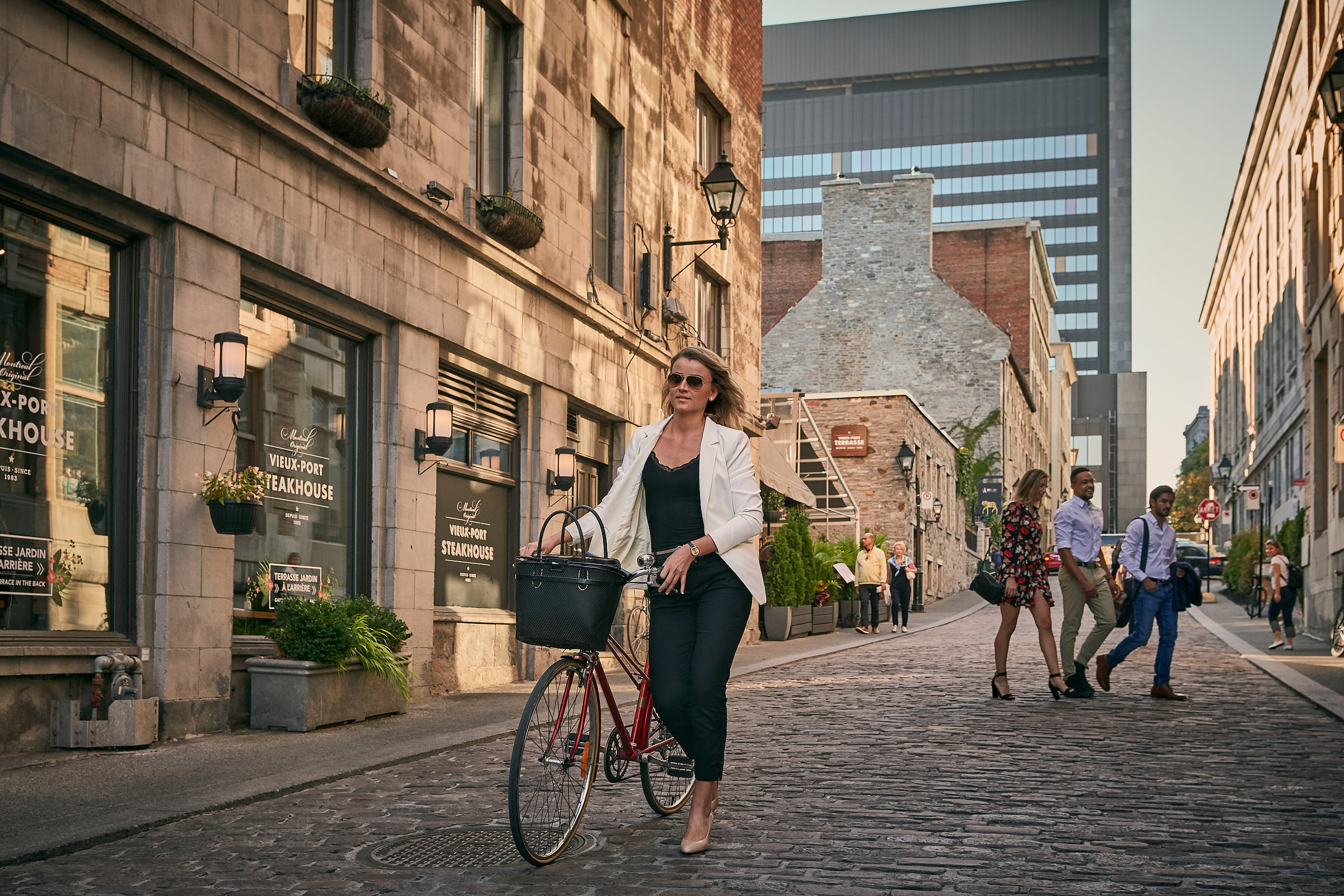 A woman walks her bike on a cobblestone street in Old Montreal 