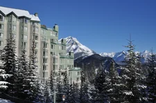 Rimrock hotel in banff in winter with snowy mountains and snow on the roof
