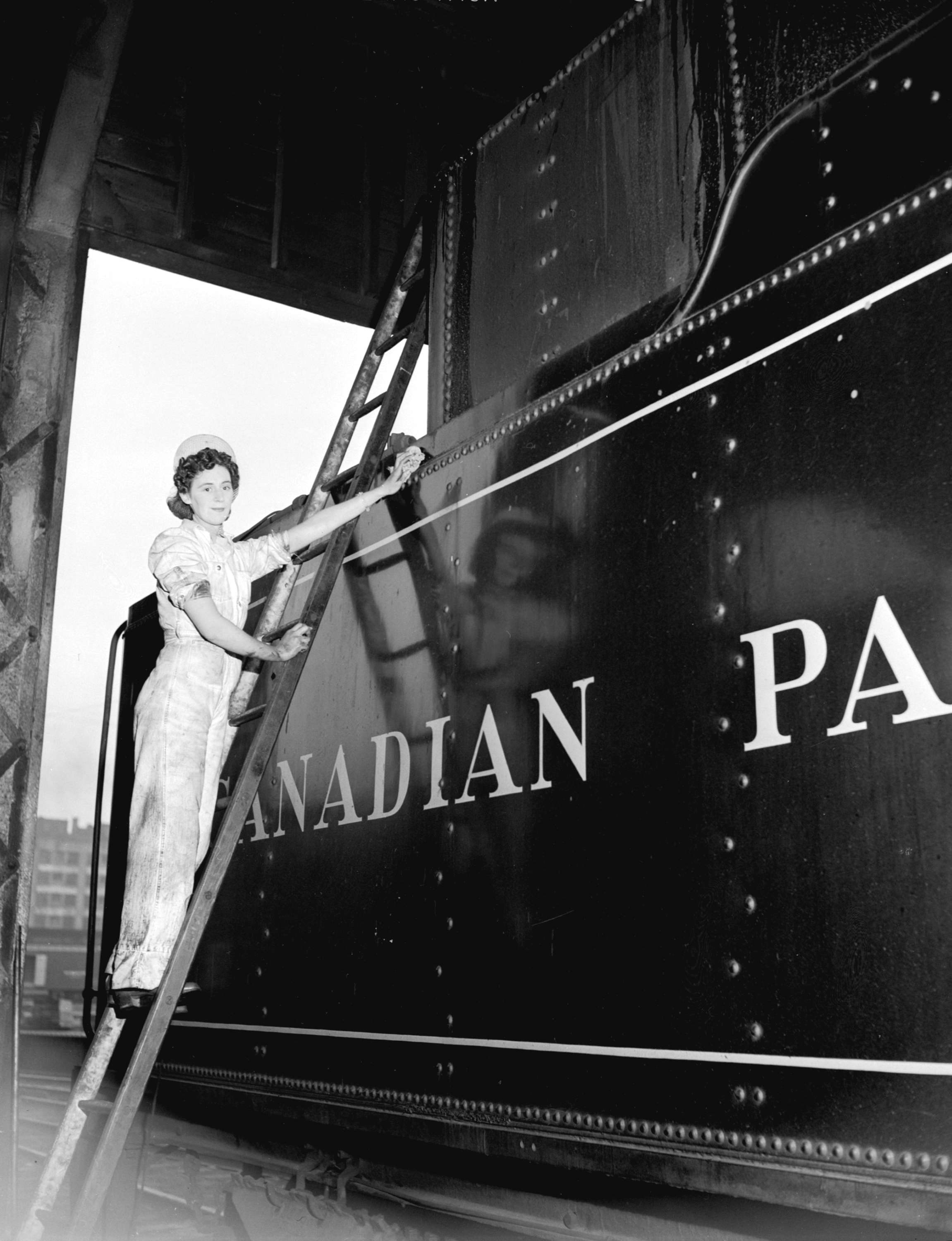 A woman washes a Canadian Pacific Rail Car in a black and white photo