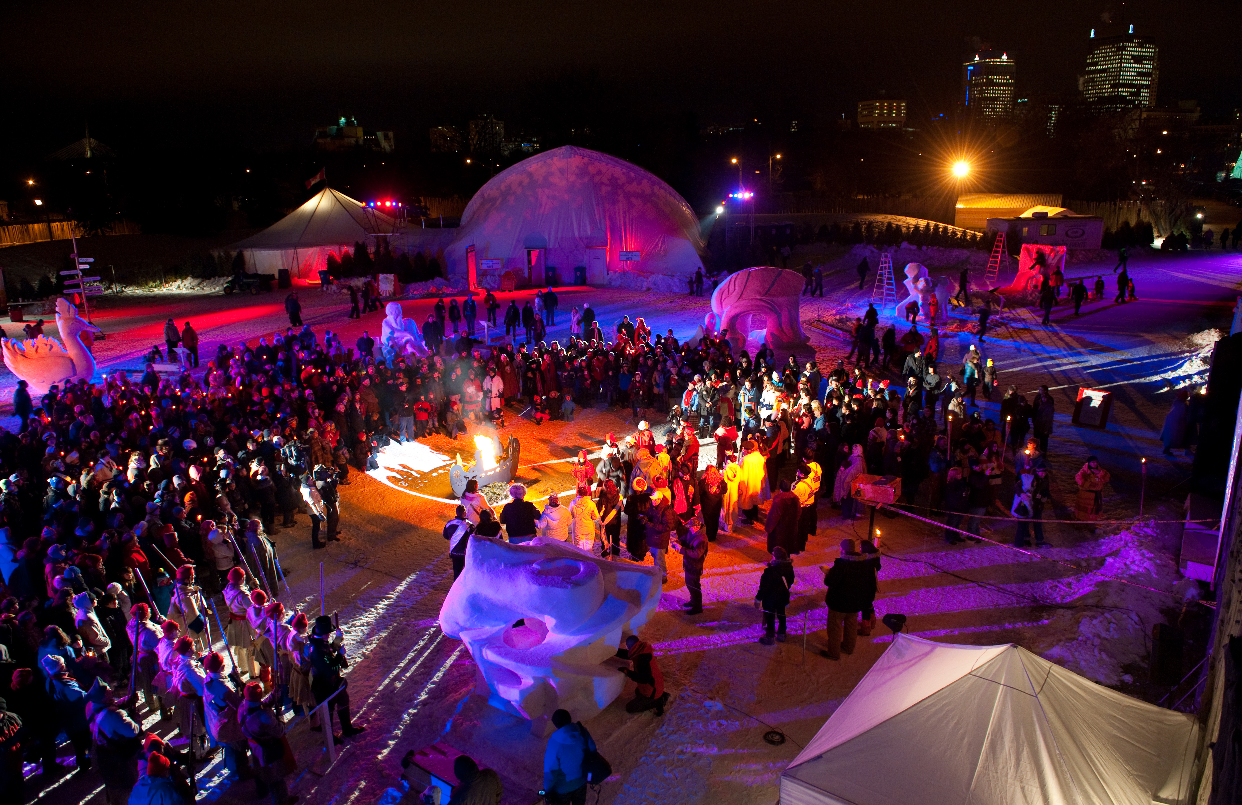 Crowd of people stand around an outdoor show at the winter Festival du Voyageur 