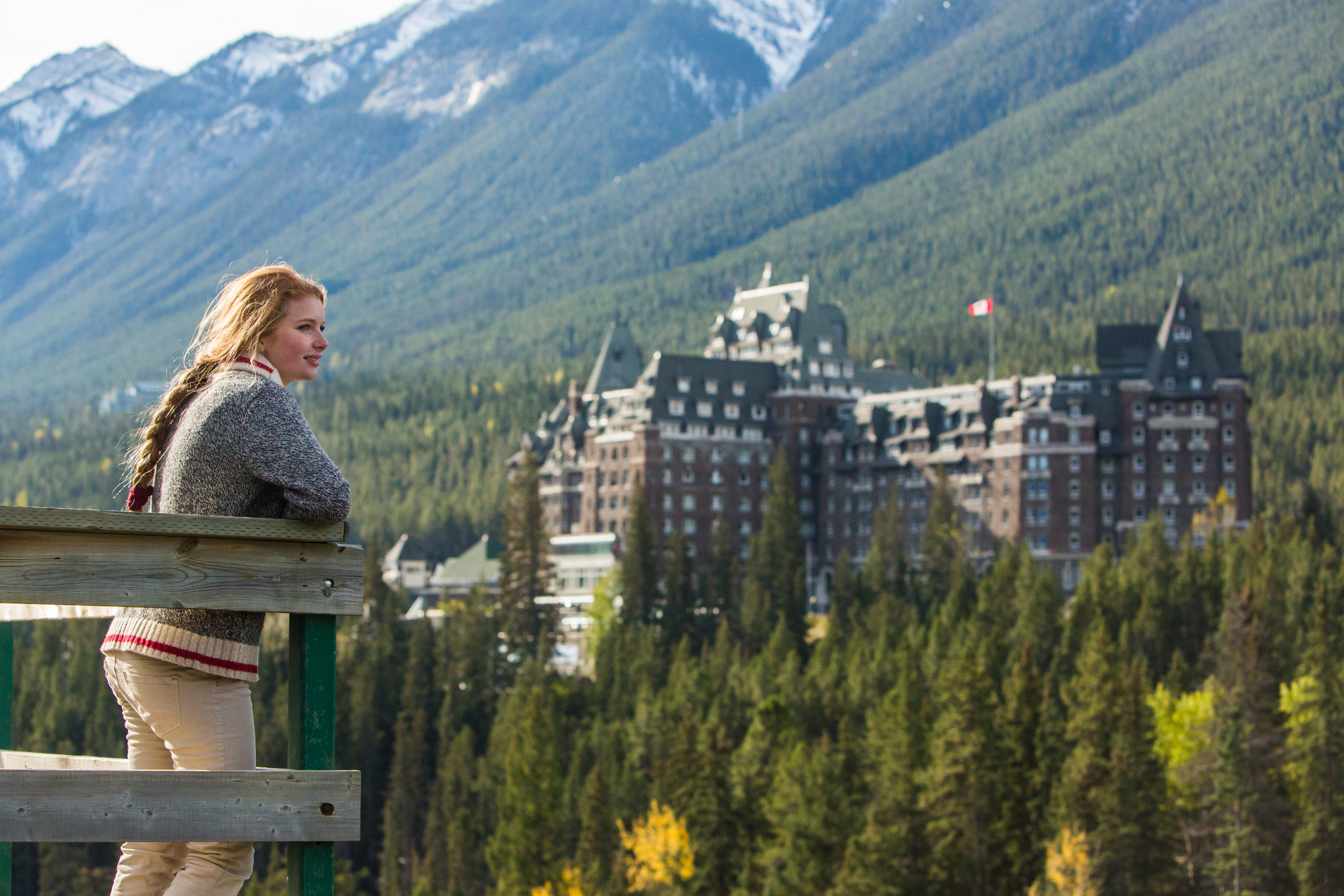 Woman standing at the Surprise Corner viewpoint with Fairmont Banff Springs hotel in the distance