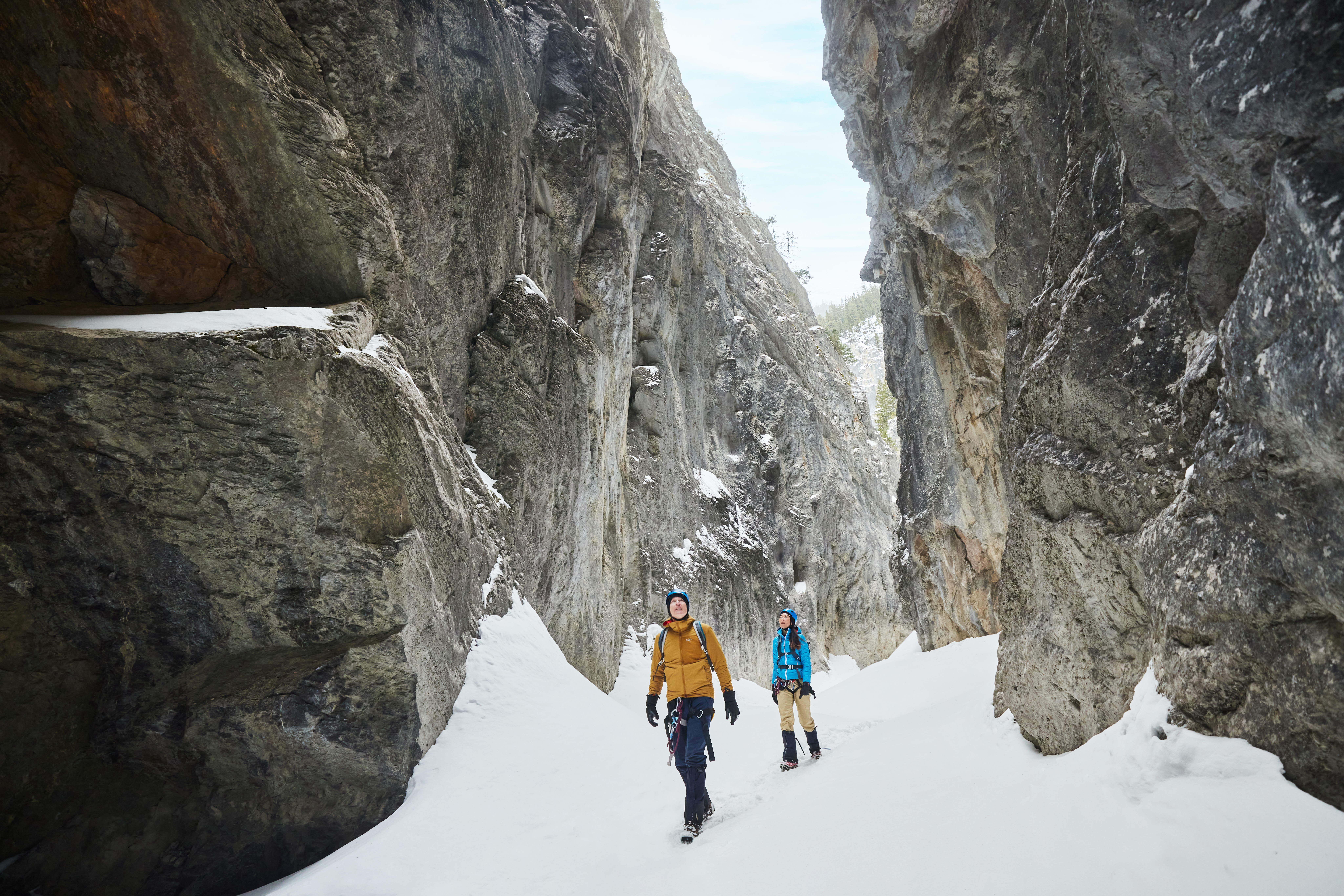A couple ice walking in canyon take in their surroundings during daytime