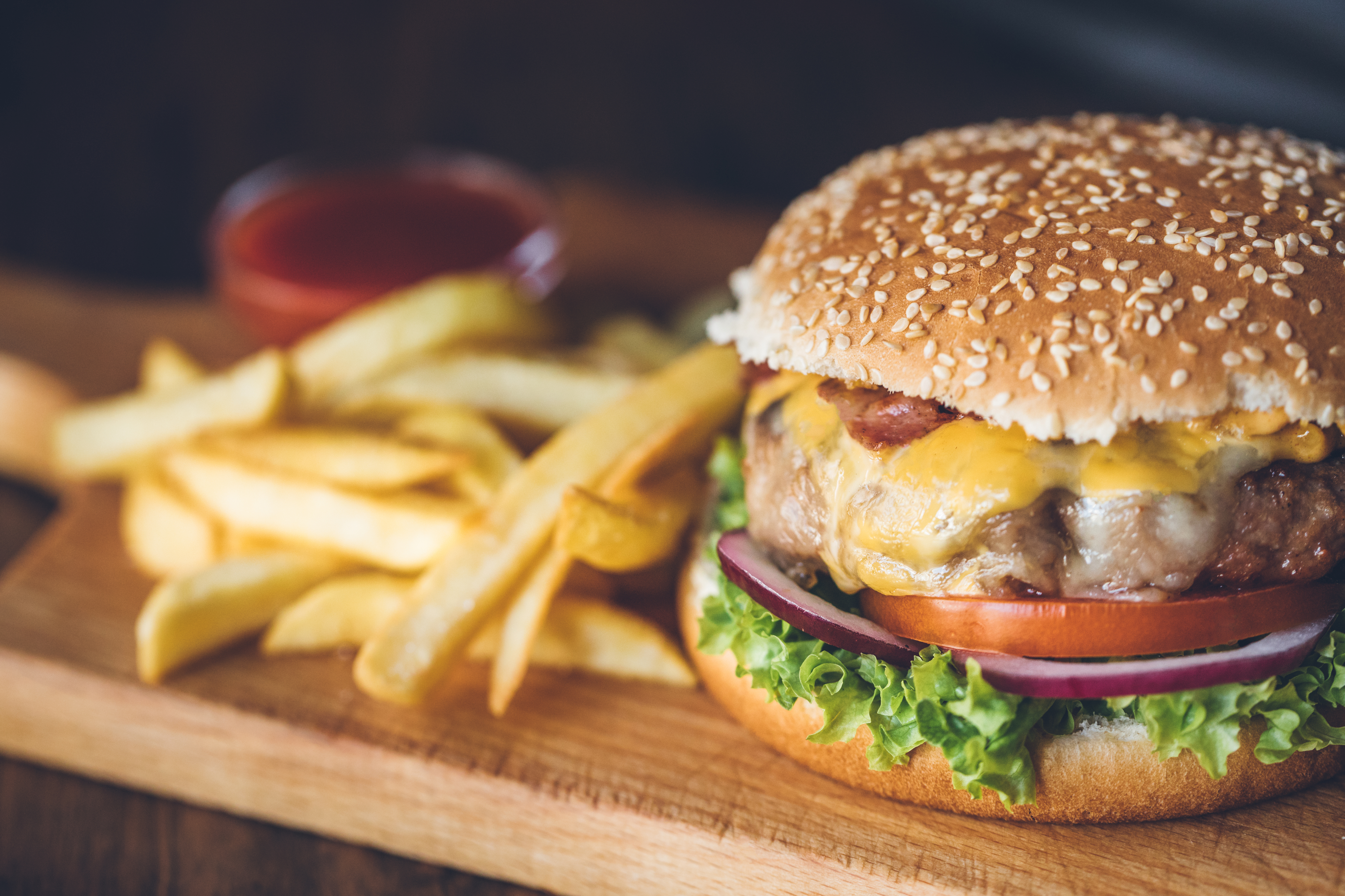 Close up of a burger and chips on a wooden serving board