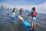 Three paddleboarders on Lake Ontario with Toronto city skyline in the distance