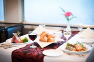 A table set with a fine dining meal with wine in a train dining car