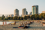 People on a beach during summer in Vancouver and city buildings behind