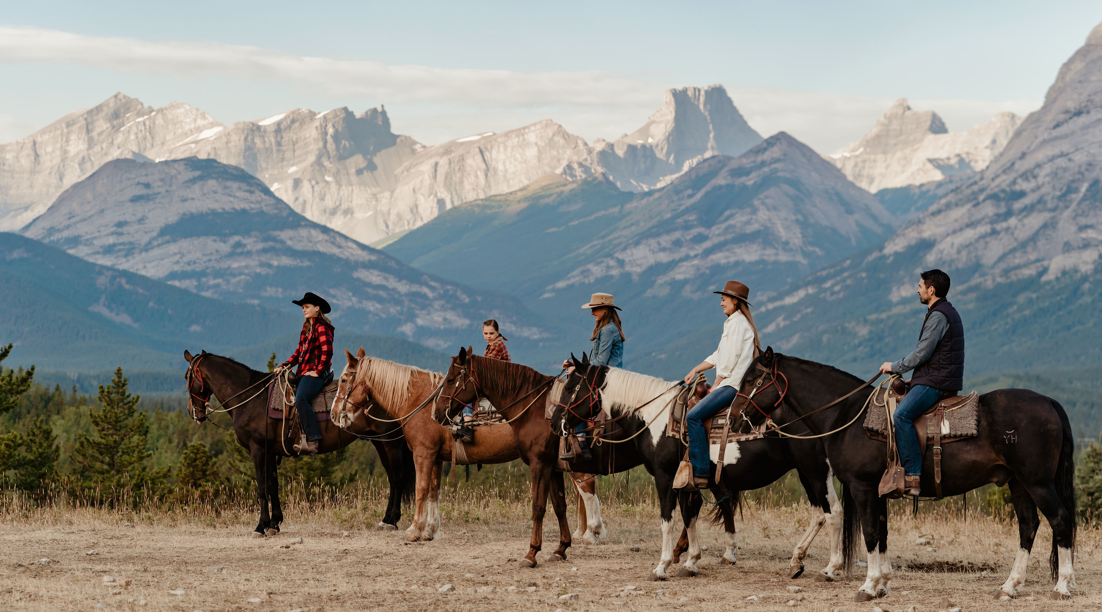 Five people on horseback in front of a mountain range