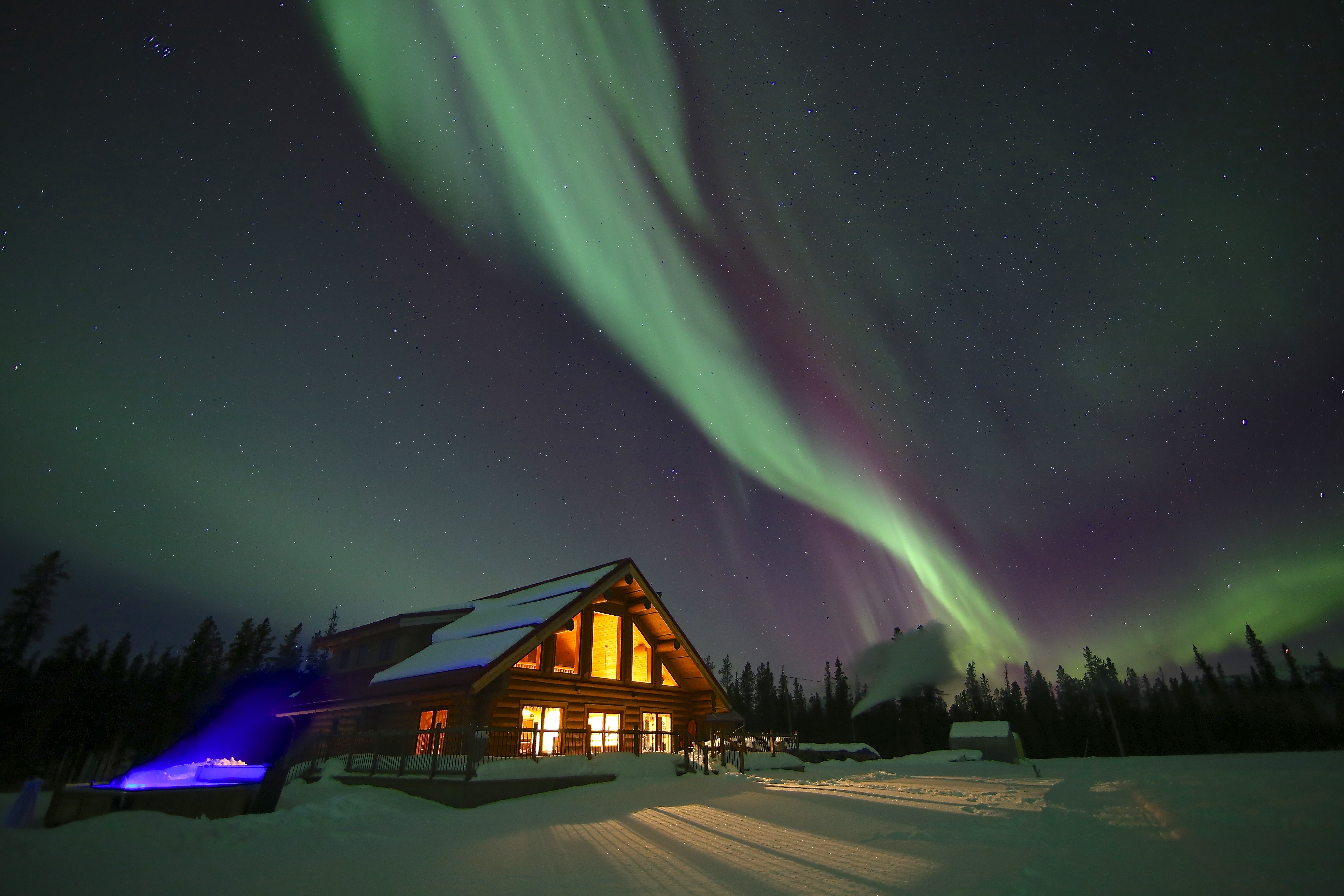 Northern lights in bright night sky by rustic cabins