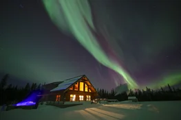 Northern lights in bright night sky by rustic cabins
